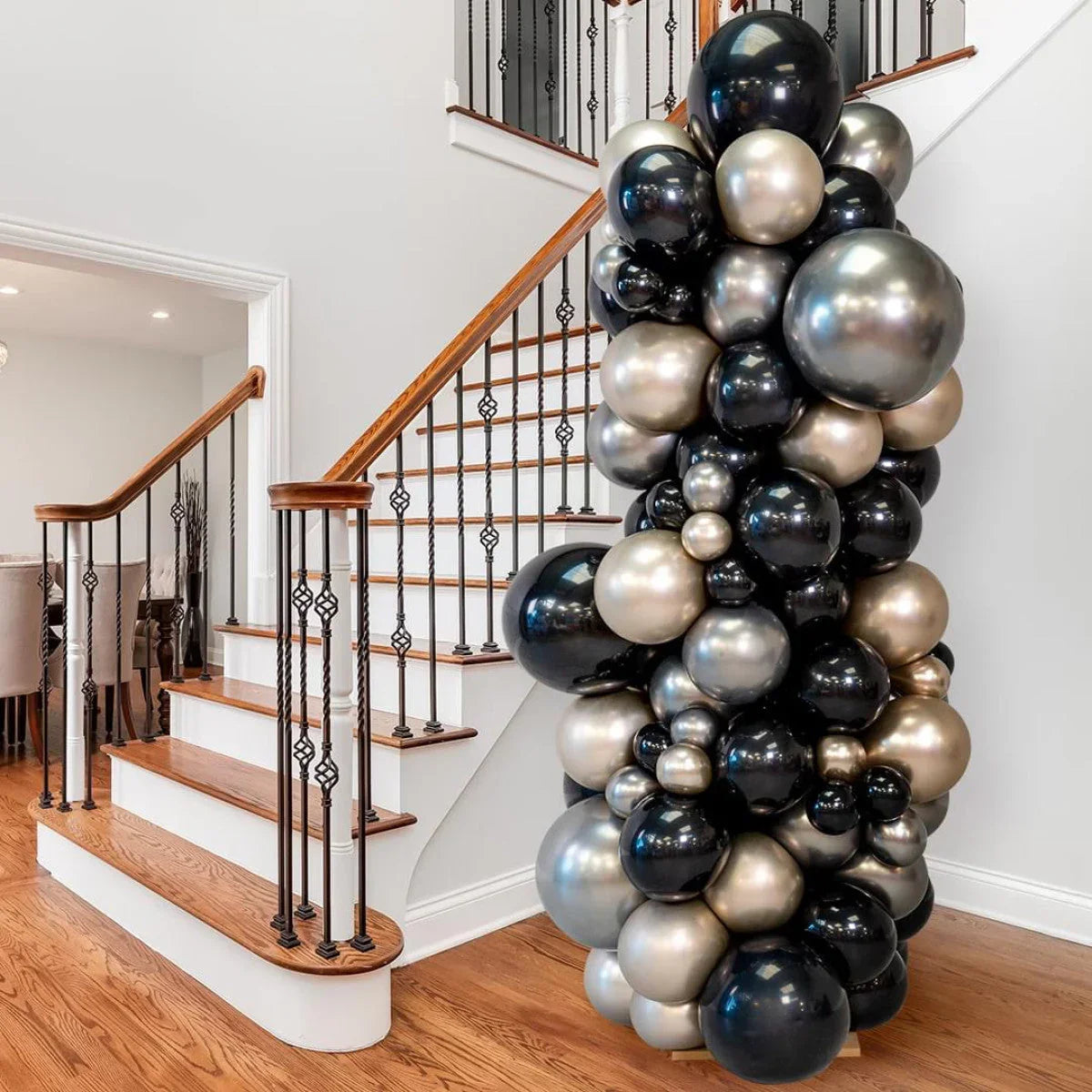 Black and champagne balloon pillar decor next to wooden staircase with iron railing in home interior