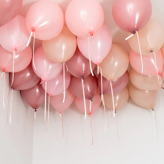 Cluster of pink, peach, and mauve helium balloons attached to ceiling with ribbons