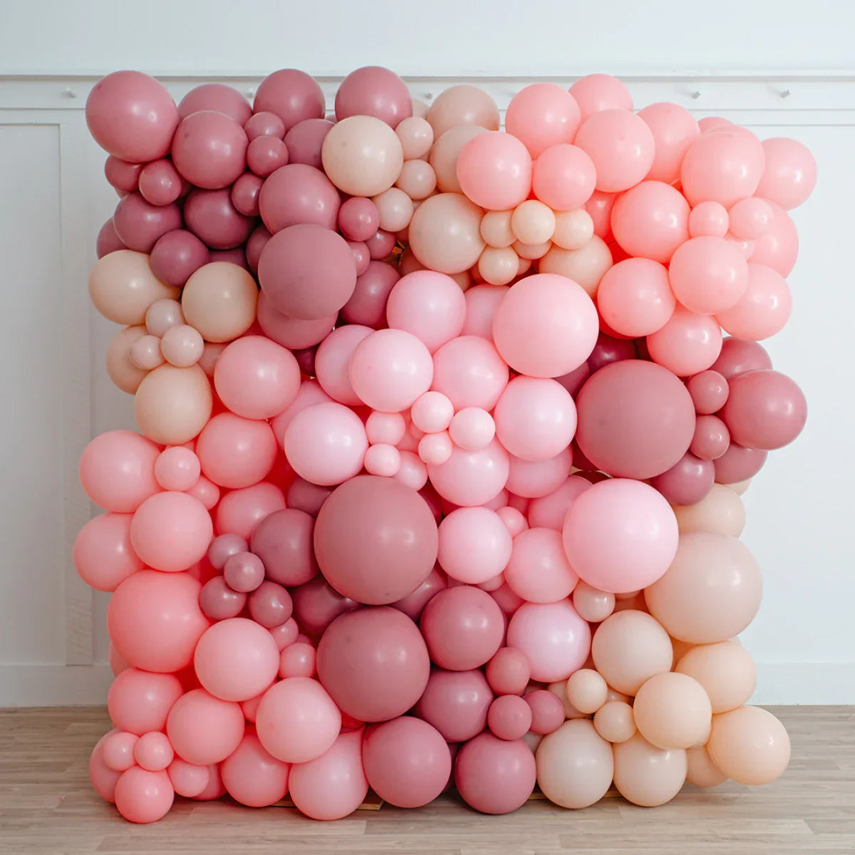 Cherry blossom balloon wall backdrop in shades of pink and peach indoors on wooden floor