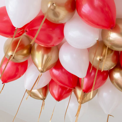 Cluster of red, white, and gold helium balloons with ribbons attached to ceiling
