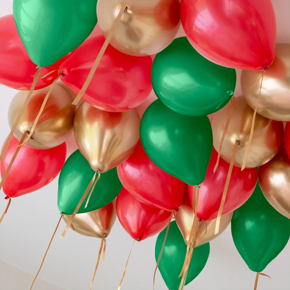 Helium balloons in red, green, and gold floating on a ceiling, perfect for Christmas decor