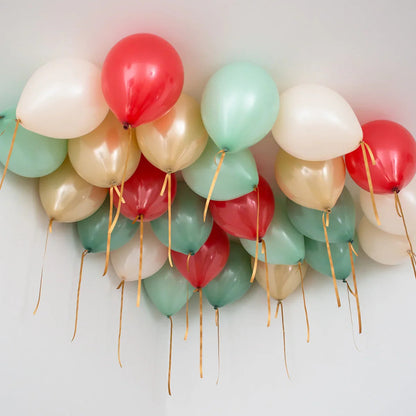 Cluster of red, green, gold, and white helium balloons attached to ceiling with gold ribbons