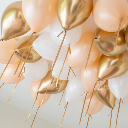 Cluster of cream, chrome gold, and white helium balloons hanging from ceiling with ribbons