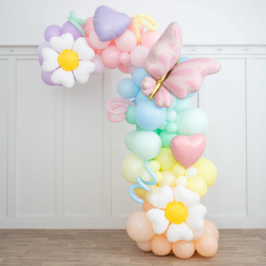 Pastel rainbow balloon arch with white daisy and pink butterfly foil balloons indoors