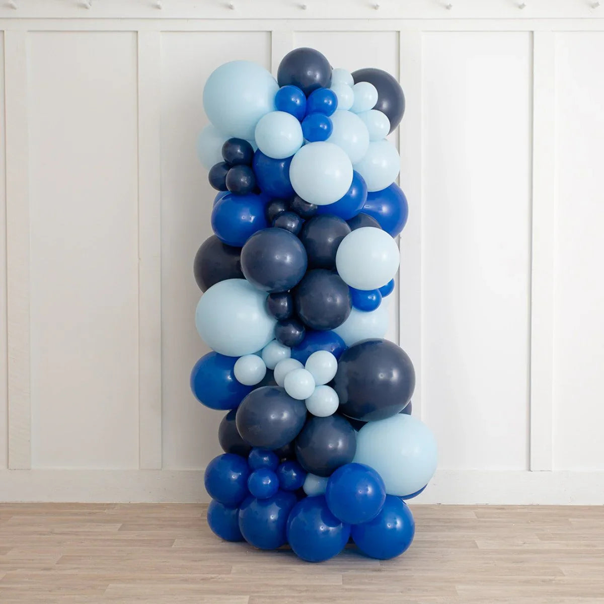 vertical balloon pillar in dark blue, royal blue, and light blue shades against white wall