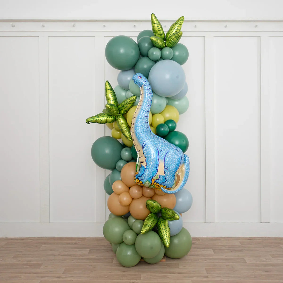 Colorful dinosaur balloon pillar with green, blue, and brown balloons and green leaf accents