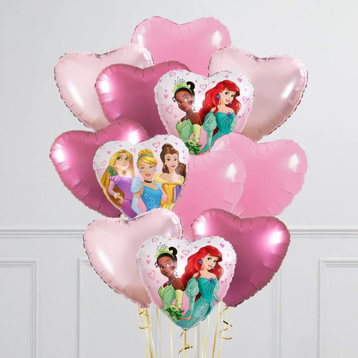 Heart-shaped foil balloons in pink shades featuring Disney princesses in a white room with wall paneling