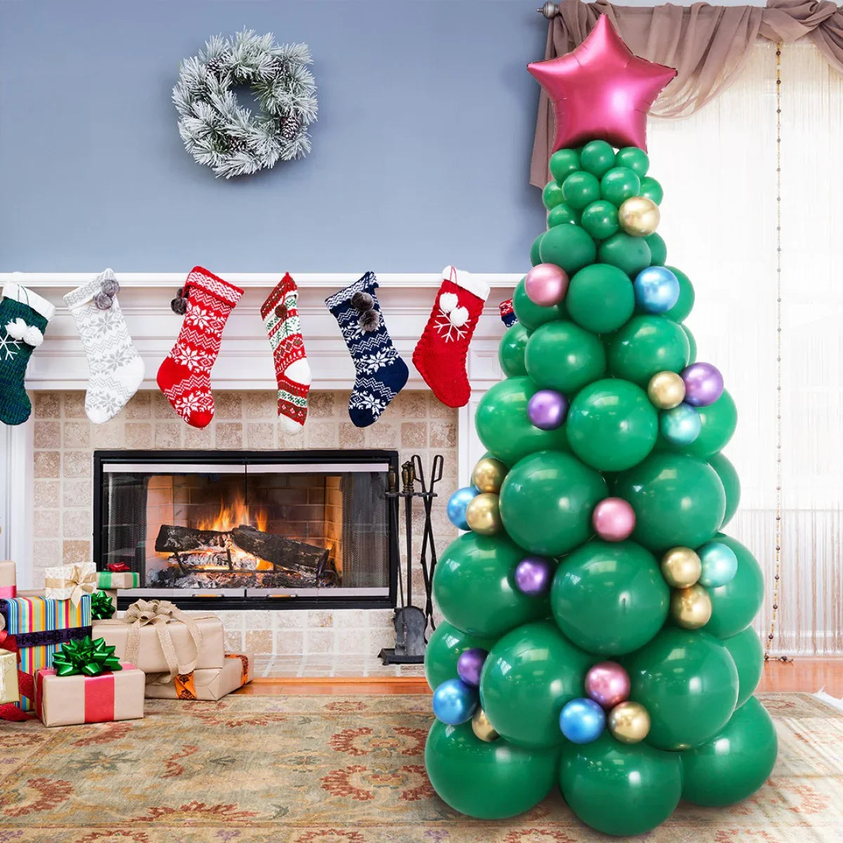 Festive green balloon Christmas tree with colorful ornaments and star topper near fireplace with stockings