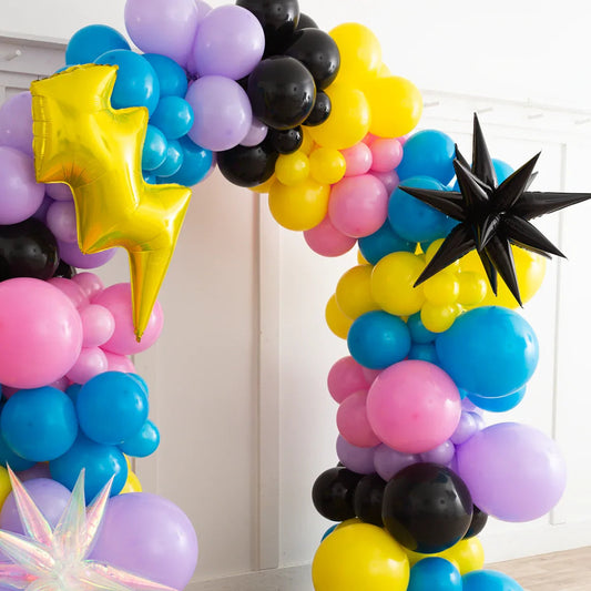 Colorful balloon arch with yellow lightning bolt and black star foil balloons in a bright room
