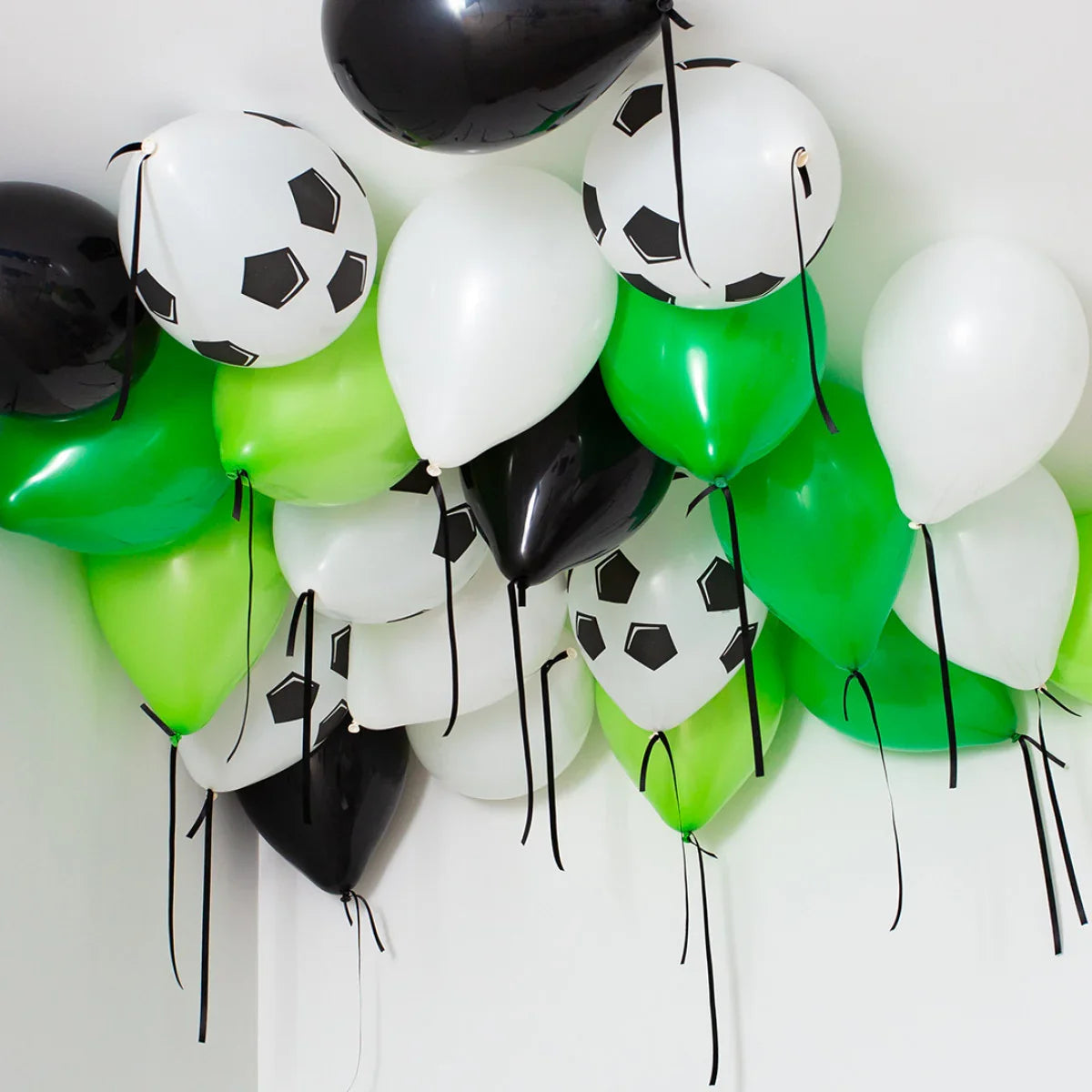 Helium football balloons in black, white, and green colors clustered on ceiling