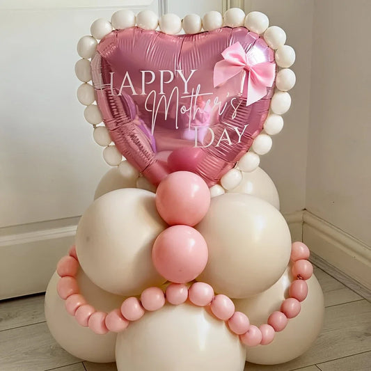 Pink heart-shaped balloon with Happy Mother's Day text, surrounded by cream and pink balloons decoration