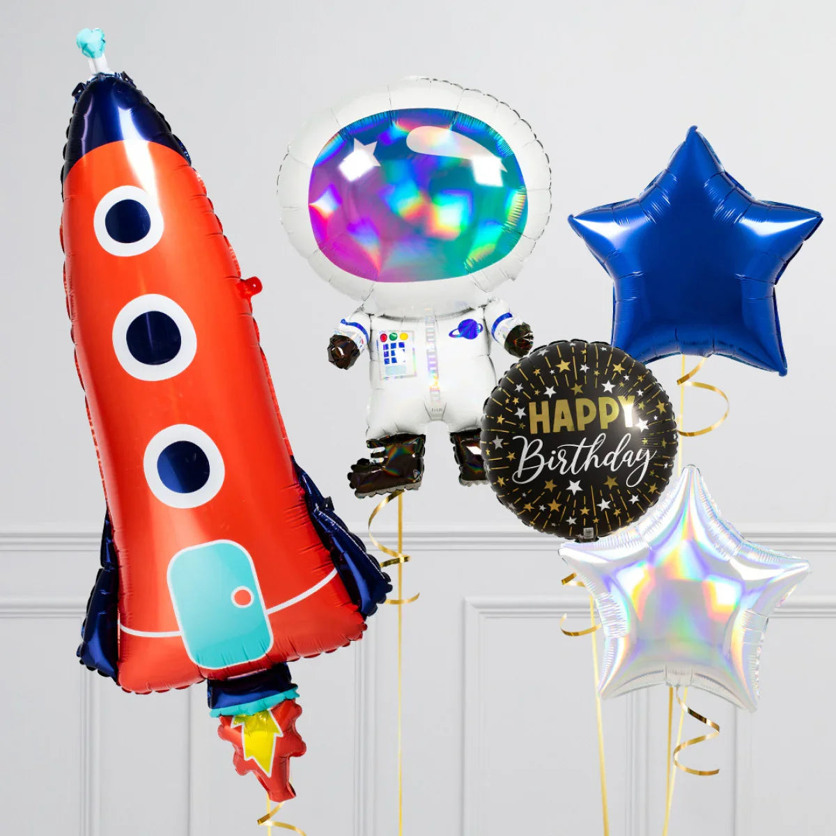 Colorful space-themed birthday balloons including a red rocket, holographic astronaut, black Happy Birthday, blue star, and silver star