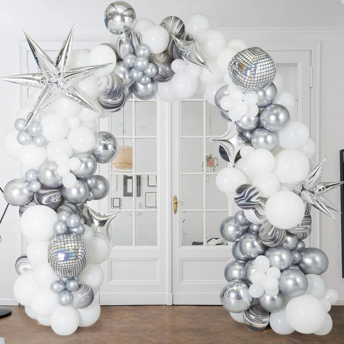 Balloon arch in white, silver, and marble patterns with star and disco ball foils in a modern indoor setting