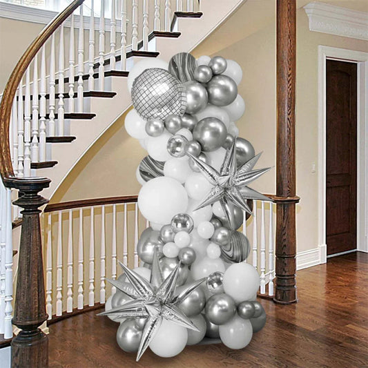 Silver and white inflated balloon pillar with star shapes in a wooden staircase hallway