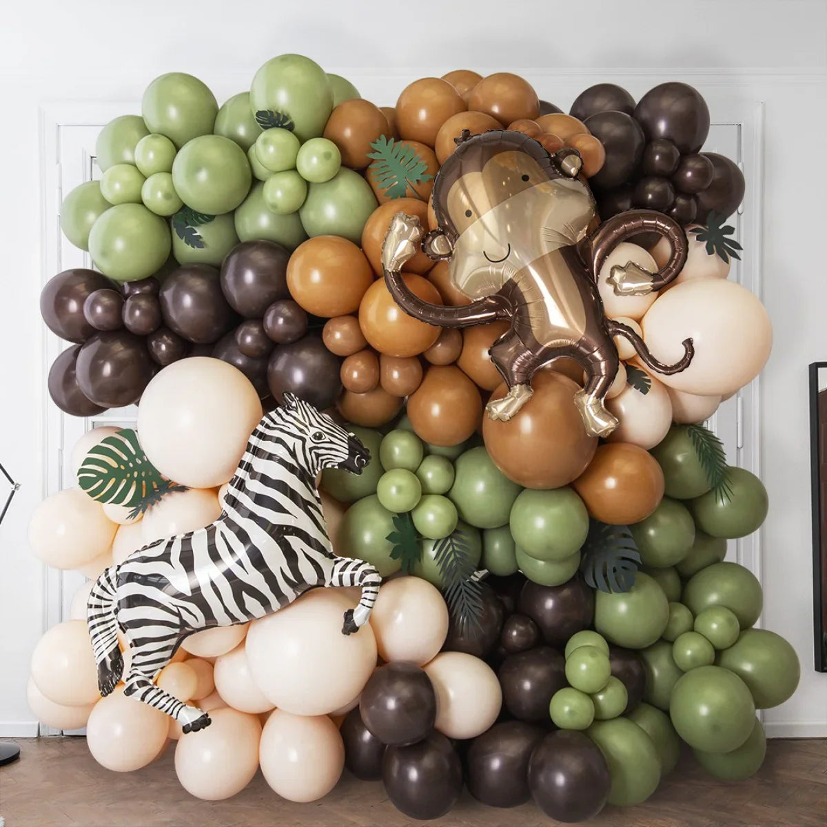 Jungle party balloon wall with green, brown, beige clusters and foil zebra, monkey balloons indoor