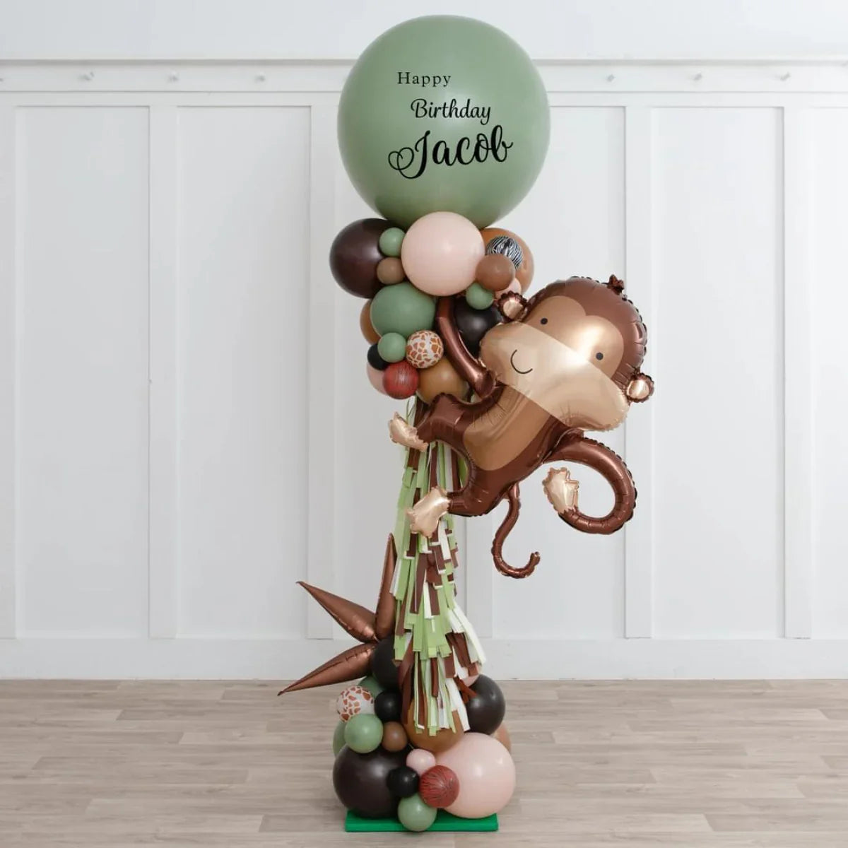 Jungle party balloon pillar with large green birthday balloon and smiling monkey foil balloon