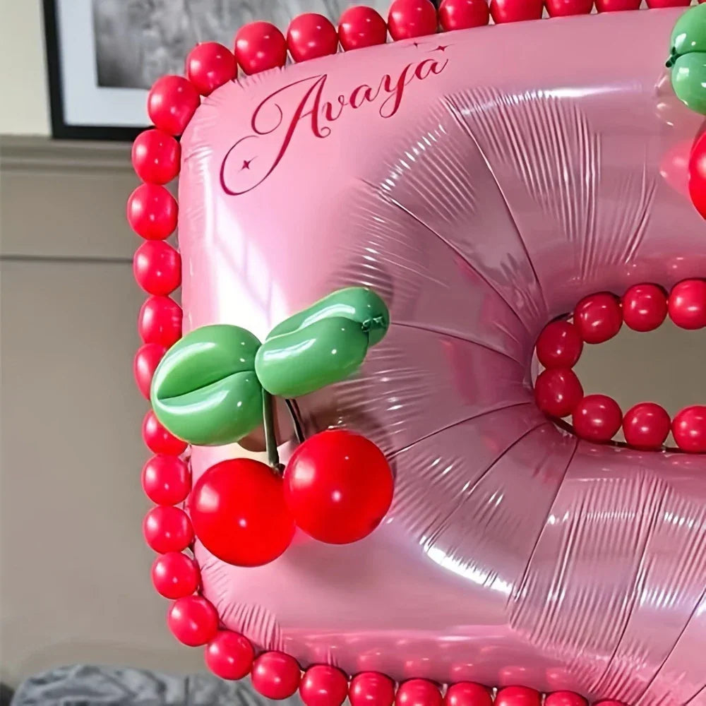 Pink cherry-themed balloon decoration with red and green balloon cherries and name Avaya