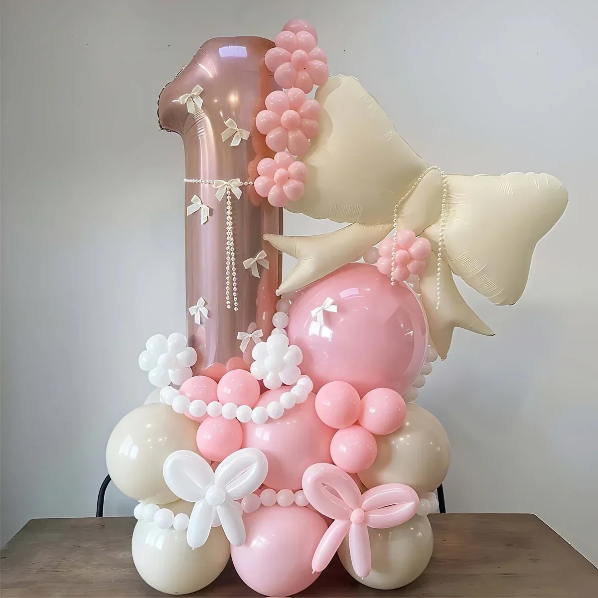 Elegant pink and cream number 1 balloon arrangement with floral and butterfly details on wooden table