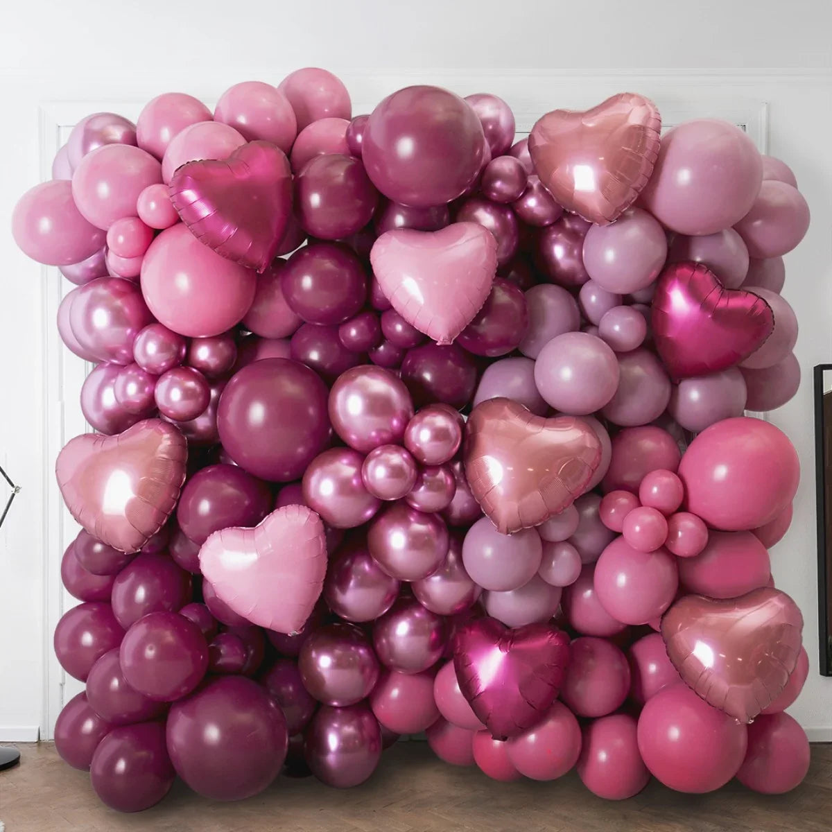 Pink, mauve, and red balloon wall with heart-shaped foil balloons for party decoration
