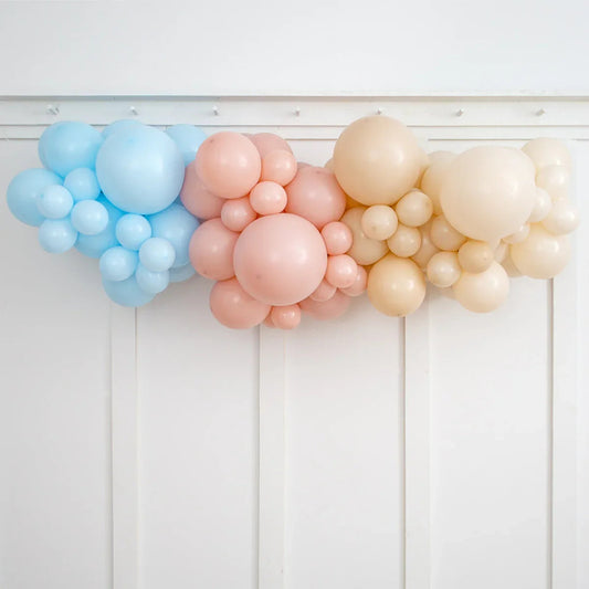 Neutral tone blue, baby pink, and cream balloon garland decoration on white wall panels