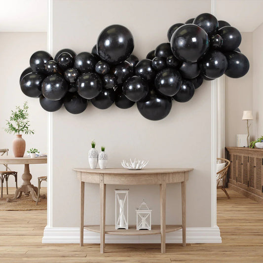 Onyx black inflated balloon garland hanging above wooden console table in modern living room