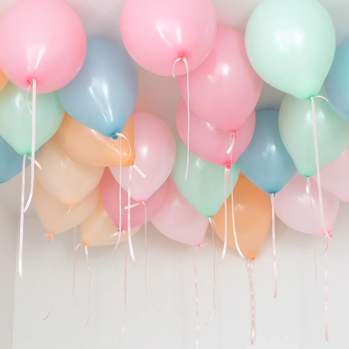 Pastel helium ceiling balloons in pink, blue, green, and orange for party decoration