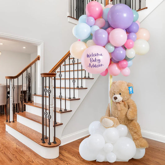 Welcome baby balloon arrangement with pastel balloons and teddy bear decoration by stairway