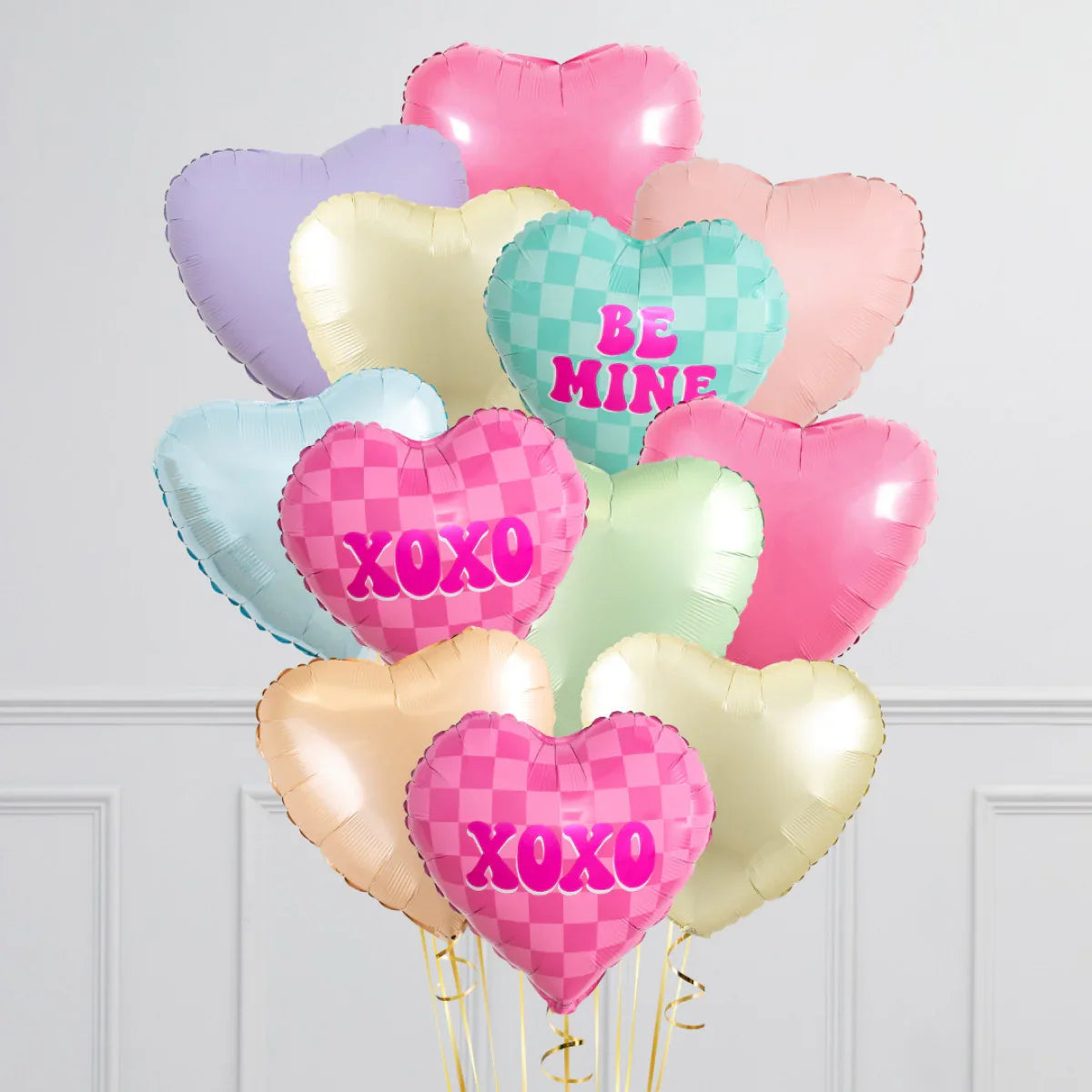 Pastel-colored heart-shaped foil balloons bouquet with checkered 'XOXO' and 'BE MINE' text