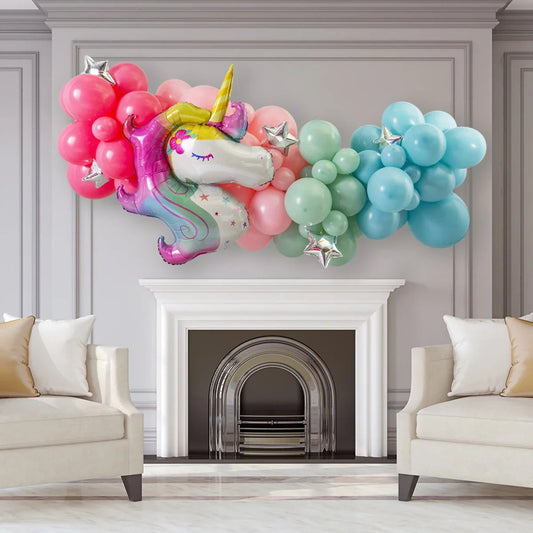 Pastel unicorn balloon garland with pink, green, blue balloons and silver star foil over white fireplace