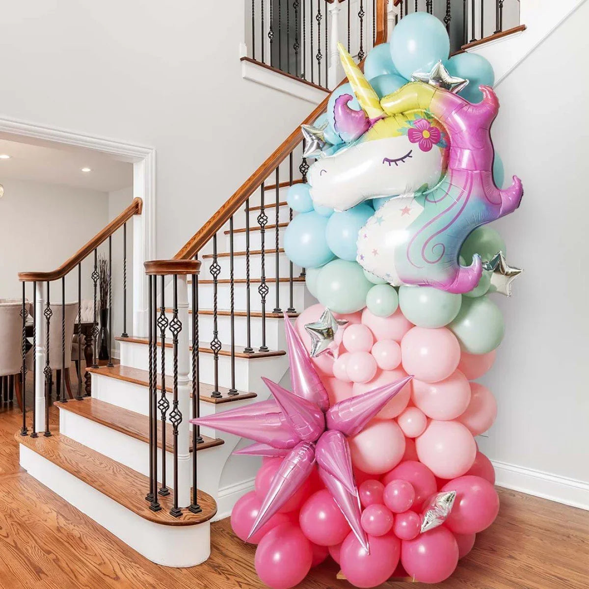 Pastel unicorn foil balloon pillar decoration with star balloons by wooden staircase in home