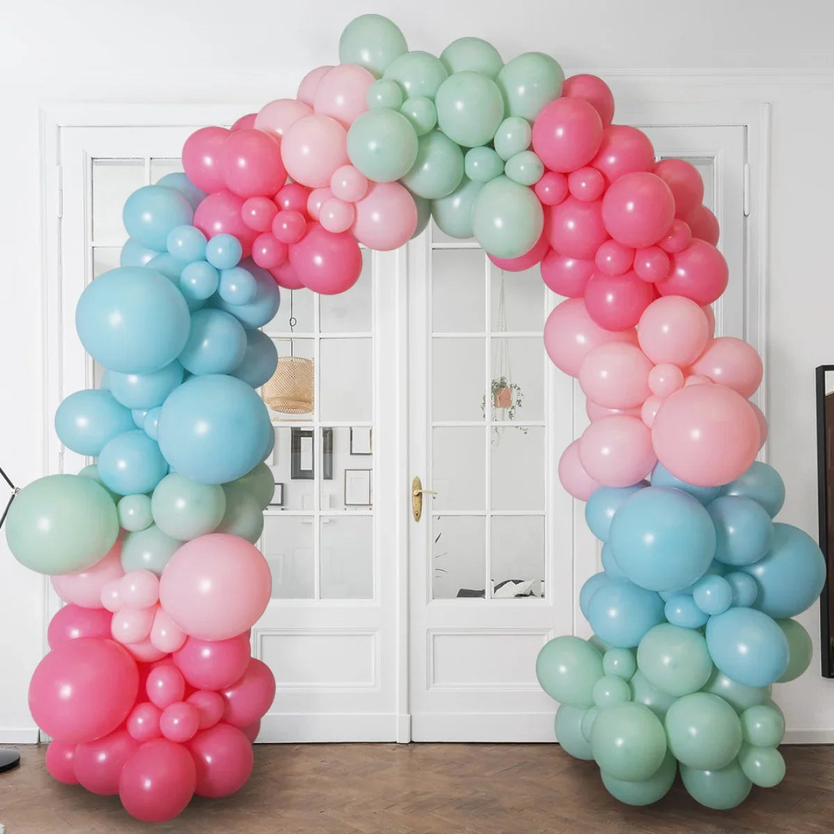 Pastel balloon arch with pink, blue, and green balloons in front of white French doors