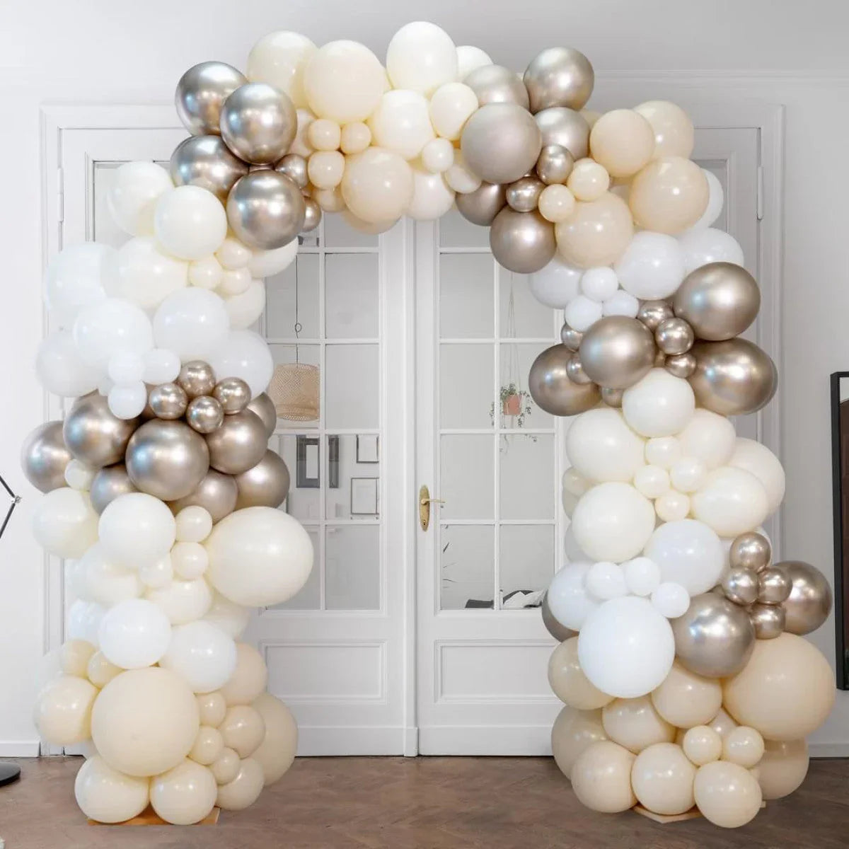 Elegant pearl and metallic silver balloon arch in neutral tones at indoor modern event space