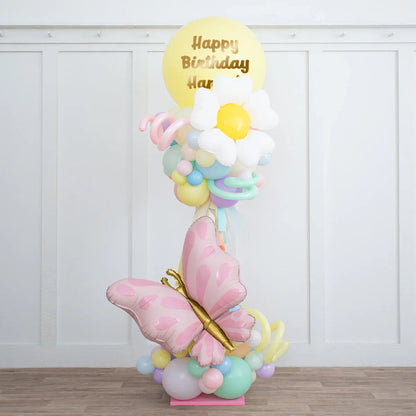 Colorful balloon pillar with pastel balloons, daisy-shaped balloon, pink butterfly, and Happy Birthday message