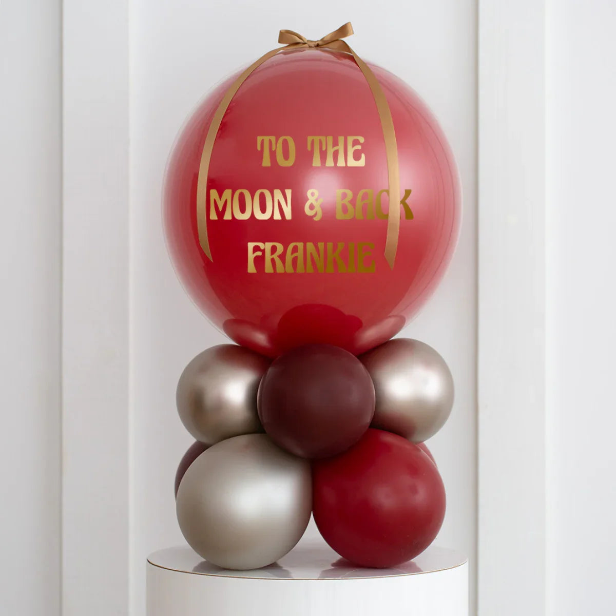 Personalised deep red pearl air-filled bubble balloon stack with gold ribbon and message 'To the Moon & Back Frankie'