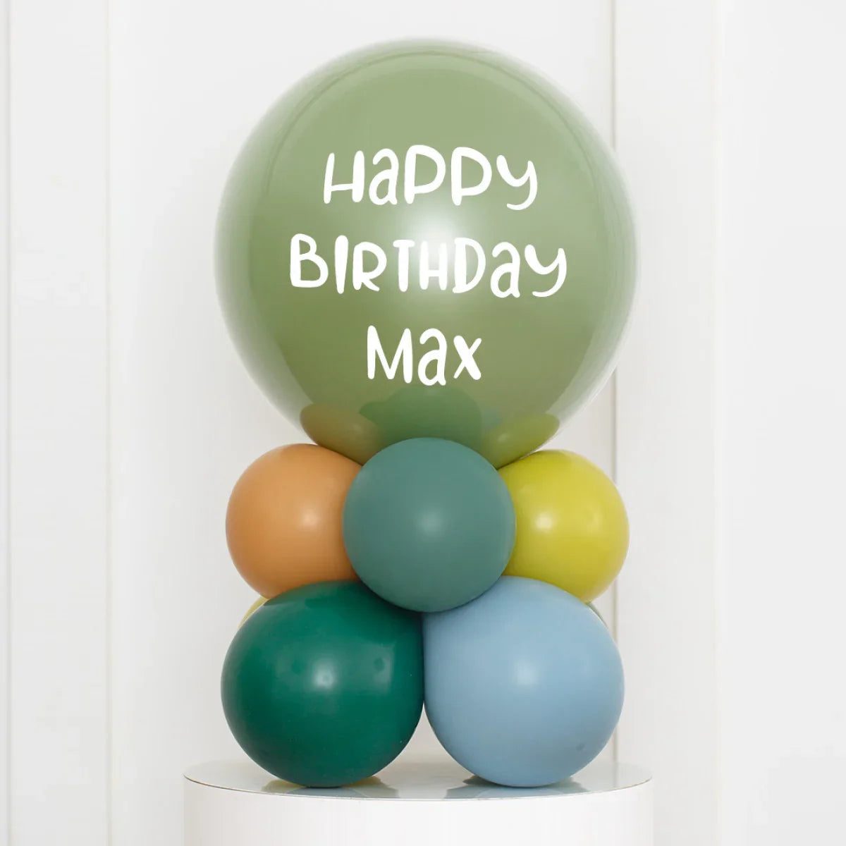 Personalised green birthday balloon with text Happy Birthday Max stacked with colorful air-filled balloons