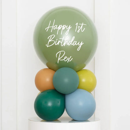 Personalized green birthday bubble balloon with text Happy 1st Birthday Rex, surrounded by smaller colorful balloons