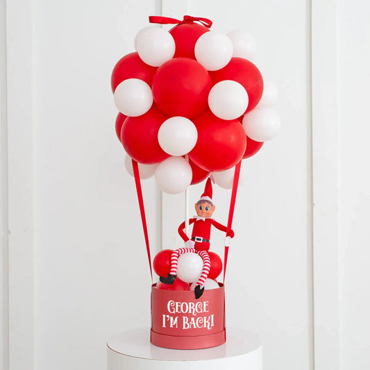 Red and white balloon hot air balloon decoration with elf doll and text George I'm Back on basket
