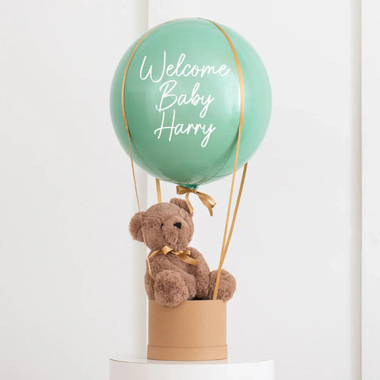 Personalised eucalyptus green balloon with 'Welcome Baby Harry' text and teddy bear in a gift box