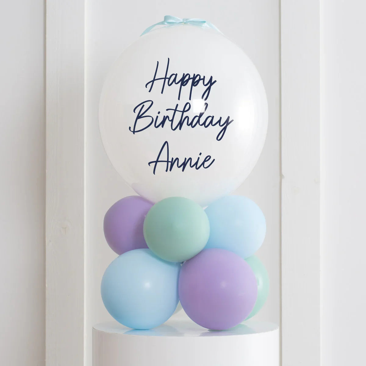 Personalized white happy birthday bubble balloon with pastel purple, blue, and green balloons stack
