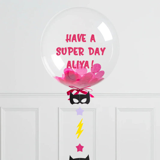 Clear bubble balloon with pink confetti and message Have a super day Aliya with black mask and colorful decorations