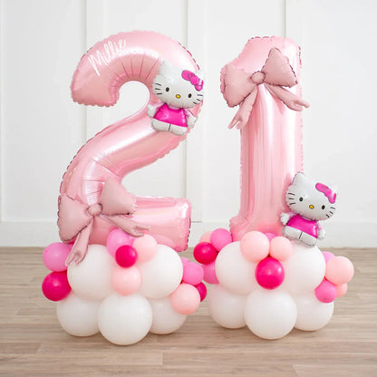 Pink Hello Kitty 21 number balloons with bows on white, pink, and red balloon bases on wooden floor