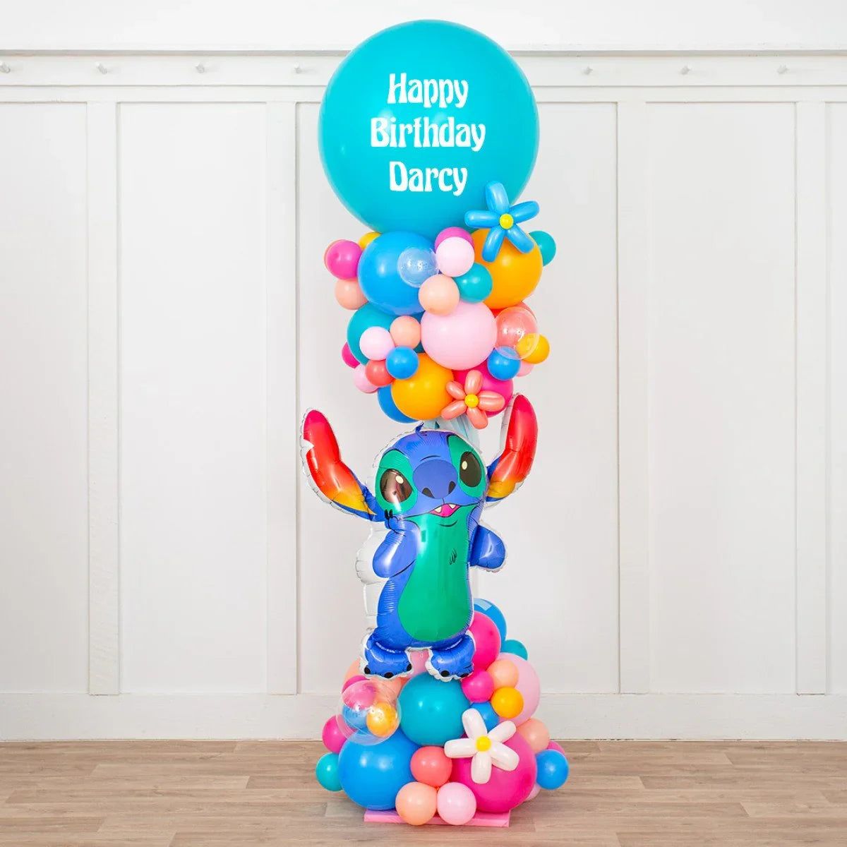Colorful birthday balloon pillar with Stitch character and Happy Birthday Darcy message