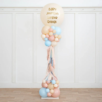 Personalized neutral pink and blue balloon pillar for baby gender reveal party in a white room