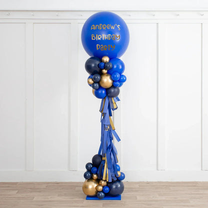 Tall sapphire blue and gold balloon pillar with Andrew's birthday party text in white room