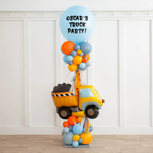 Personalized balloon pillar with yellow dump truck and blue balloon reading 'Oscar's Truck Party'