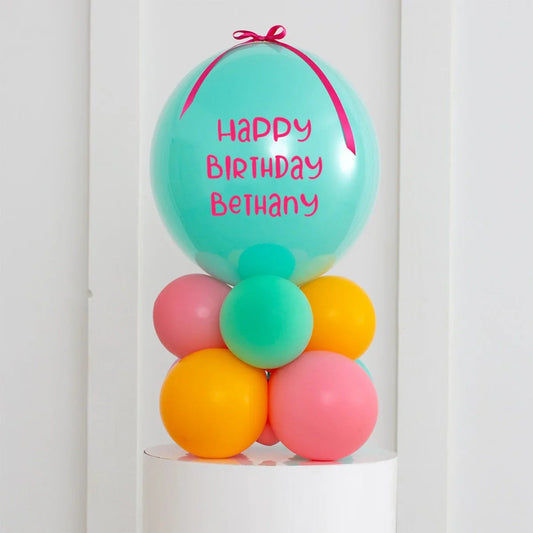 Personalised air-filled bubble balloon stack with teal top balloon saying Happy Birthday Bethany in pink