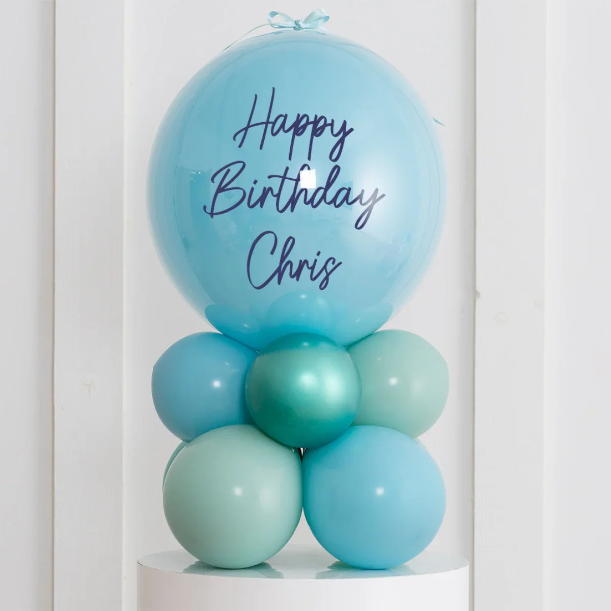 Personalized blue birthday balloon stack with Happy Birthday Chris text on air-filled bubbles