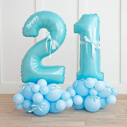 Blue number 21 balloon display with personalized name Timmy and baby blue bow clusters on wooden floor