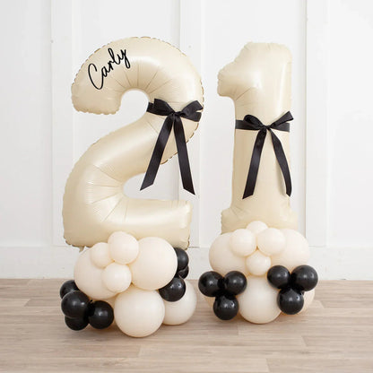 Ivory inflated number 21 balloon stack with personalized name Carly and black bow decorations