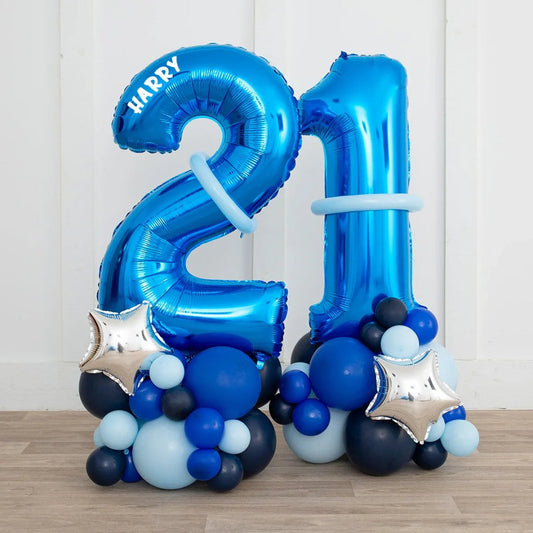 Blue metallic number 21 balloon stack with personalized name Harry and star accents on wooden floor